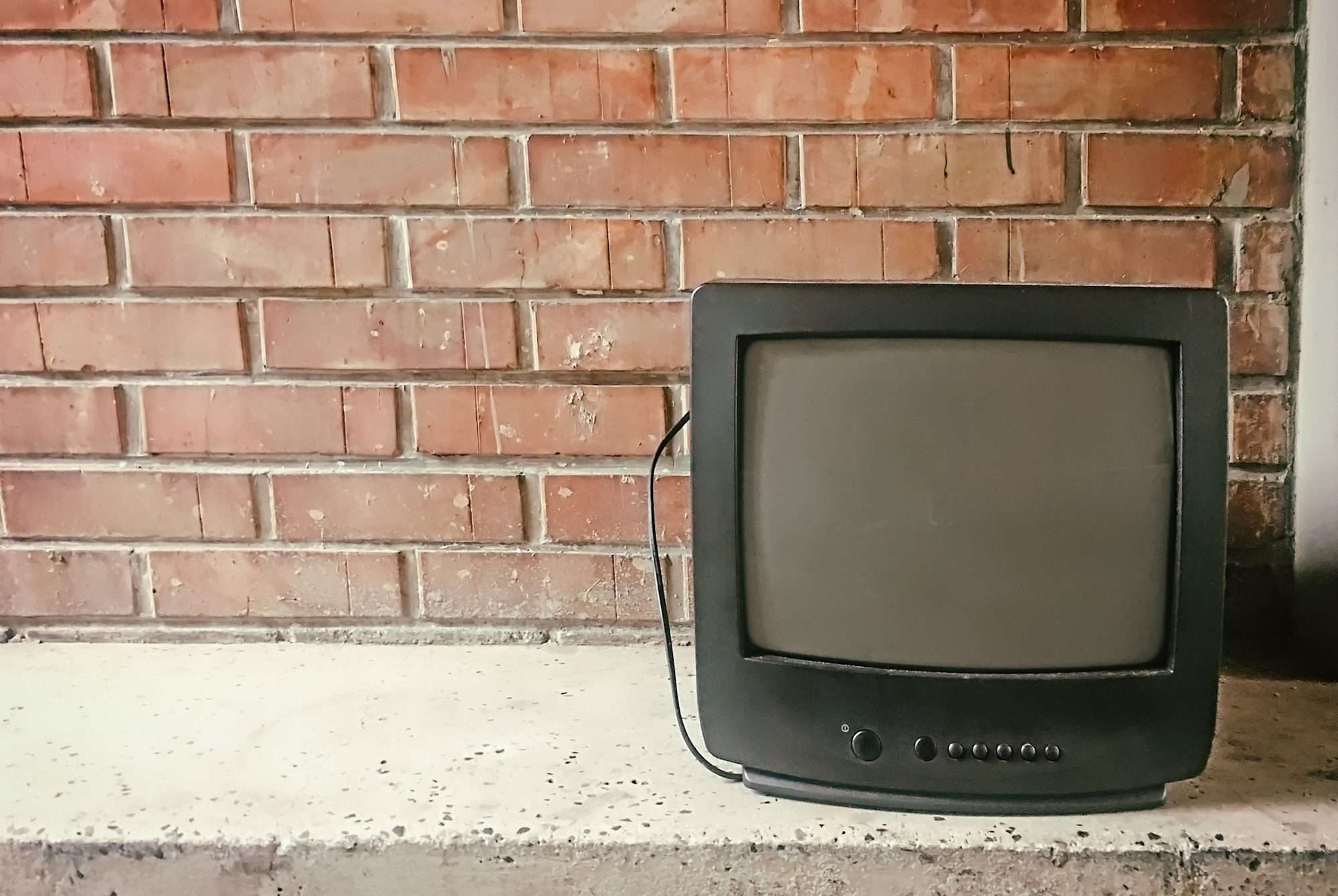 Abandoned old tv against brick wall