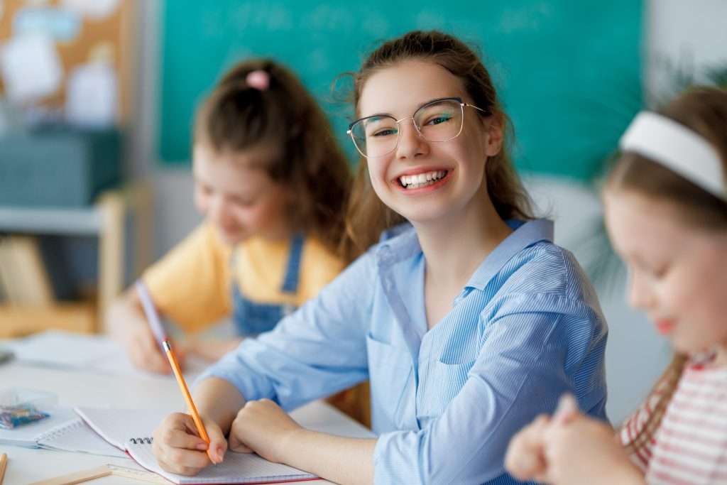 Fröhliche Kinder an einem Tisch im Klassenzimmer, Foto: envato elements